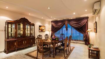 A dining area with a wooden table, chairs, a cabinet, and a window with curtains.
