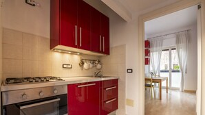 A kitchen with red cabinets, a gas stove, and a sink. - Open Space Apartment near Lambrate Station (M2 and FS) & Politecnico (Milano)