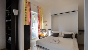 A modern bedroom with a bed, bedside table, lamp, and a view of the outside. - Open Space Apartment near Lambrate Station (M2 and FS) & Politecnico (Milano)