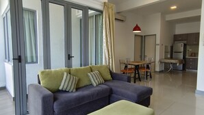 A modern living room with a sofa, ottoman, and dining area. - Rasa Sayang at The Loft Imago (Kota Kinabalu)