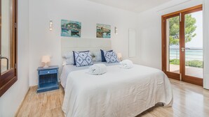Quarto com cama, mesa de cabeceira, janela com vista e obras de arte na parede.