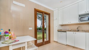 Cozinha com armários brancos, micro-ondas embutido e área de refeições com mesa e cadeiras.