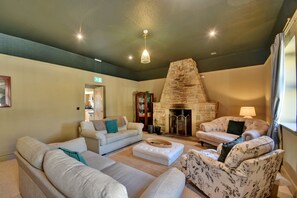 Uma sala de estar acolhedora com lareira de pedra, sofás confortáveis e uma luminária de teto moderna.