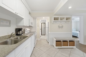 A modern kitchen with white cabinetry, a granite countertop, and a built-in sink.