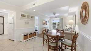 A dining area with a round table and chairs, a white bench, and a ceiling fan.