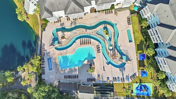 An aerial view of a resort with a large pool, sun loungers, and a mural.