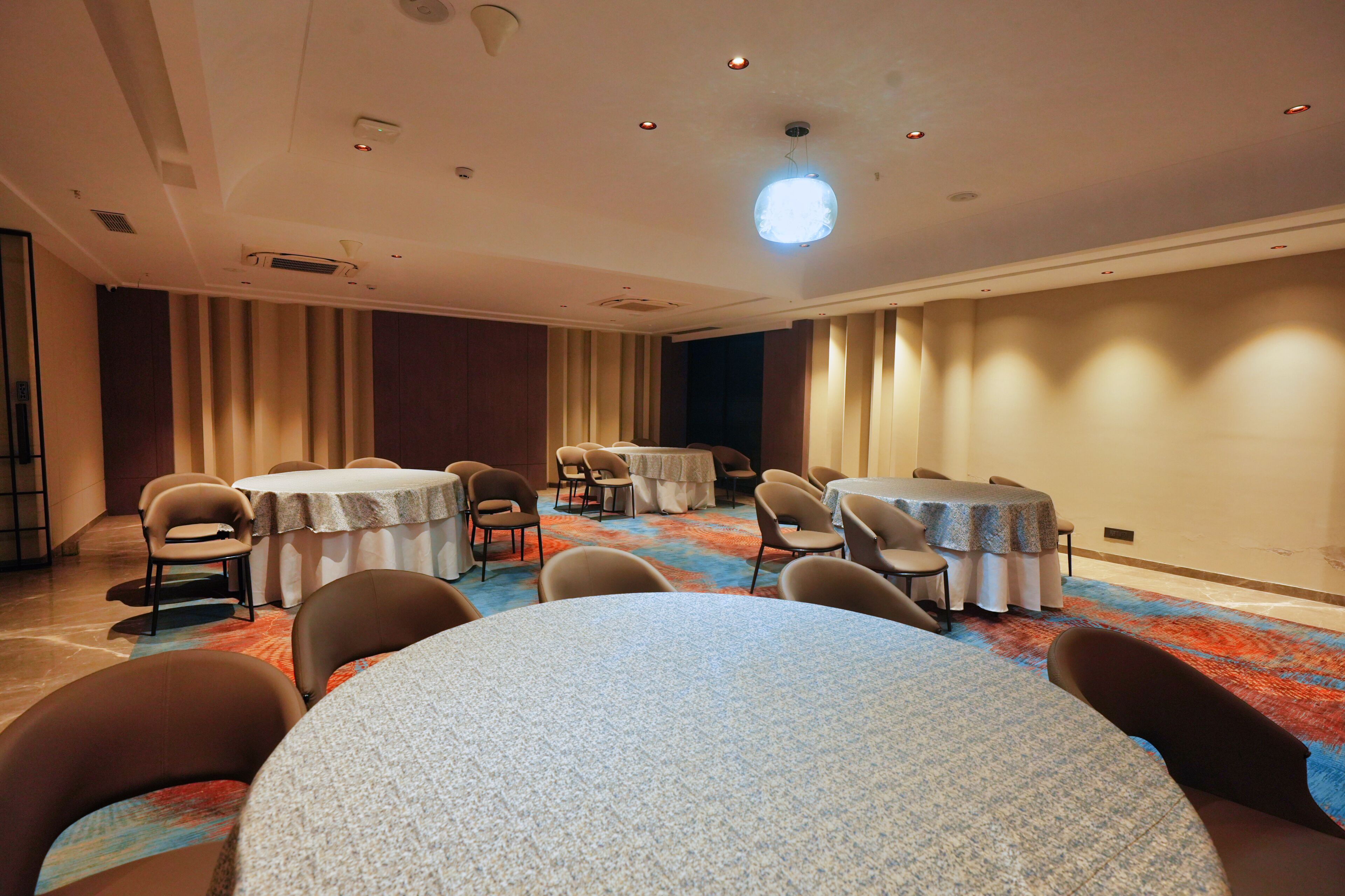 A conference room with round tables, chairs, and a carpeted floor.