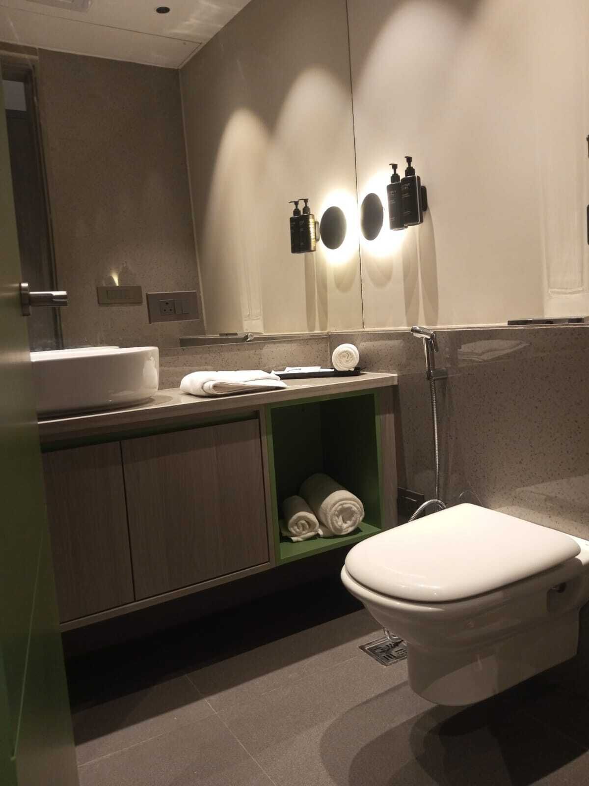 Ein modernes Badezimmer mit Toilette, Waschbecken und Stauraum für Handtücher.