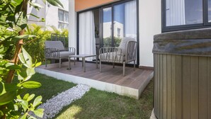 A modern outdoor patio with a seating area, a small table, and a hot tub. - NOK Modern 1BR With Terrace by Vistacana Rentals (Punta Cana)