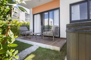 Eine moderne Außenpatio mit Sitzgelegenheit, einem kleinen Tisch und einem Whirlpool.