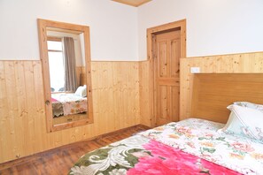 A wooden-paneled room with a bed, a mirror, and a door.