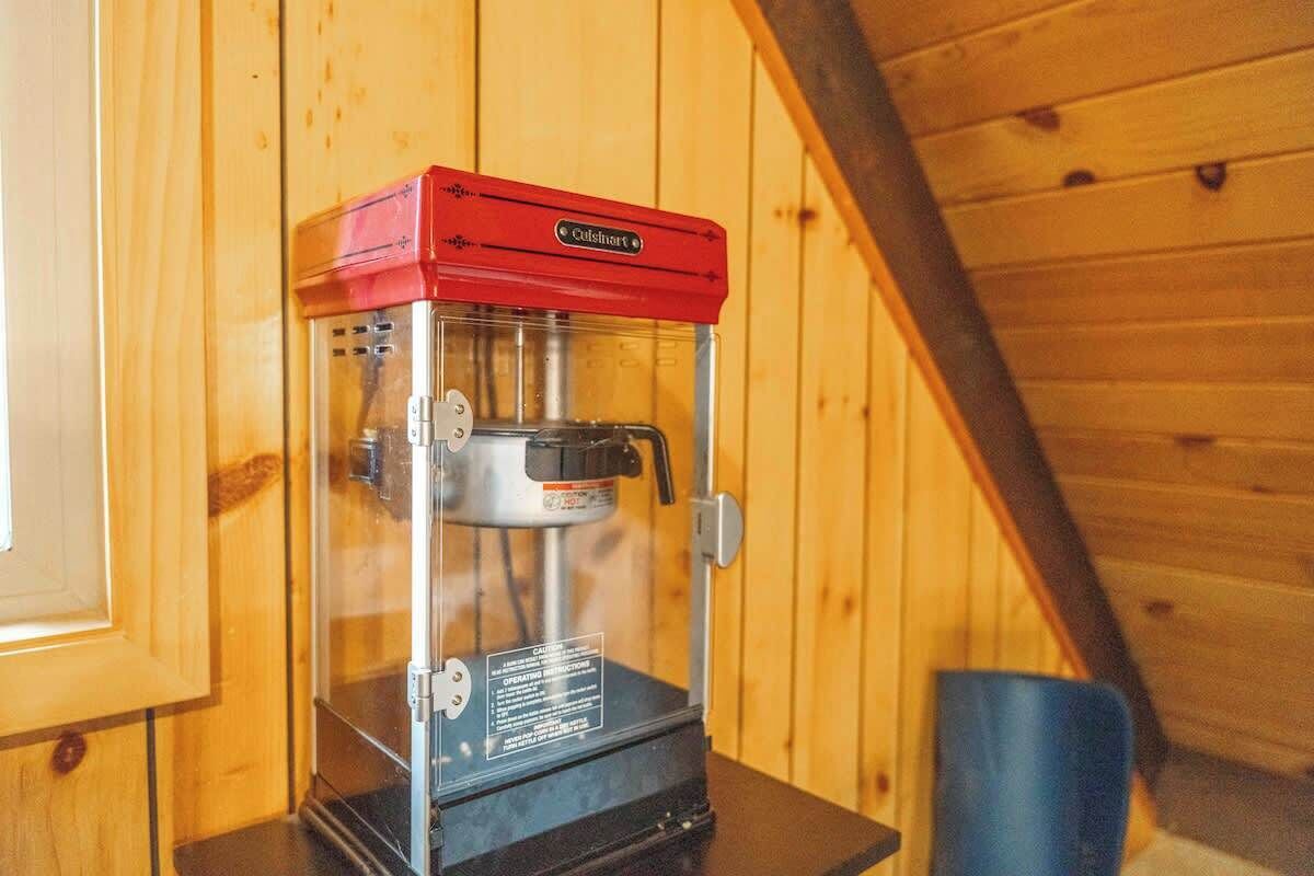 A red coffee machine in a wooden cabin with a sloped ceiling.