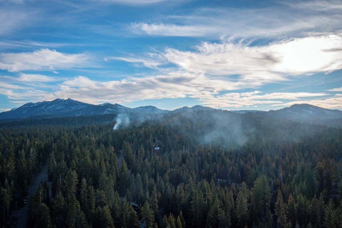 Paesaggio montuoso con fitte foreste e cielo sereno.