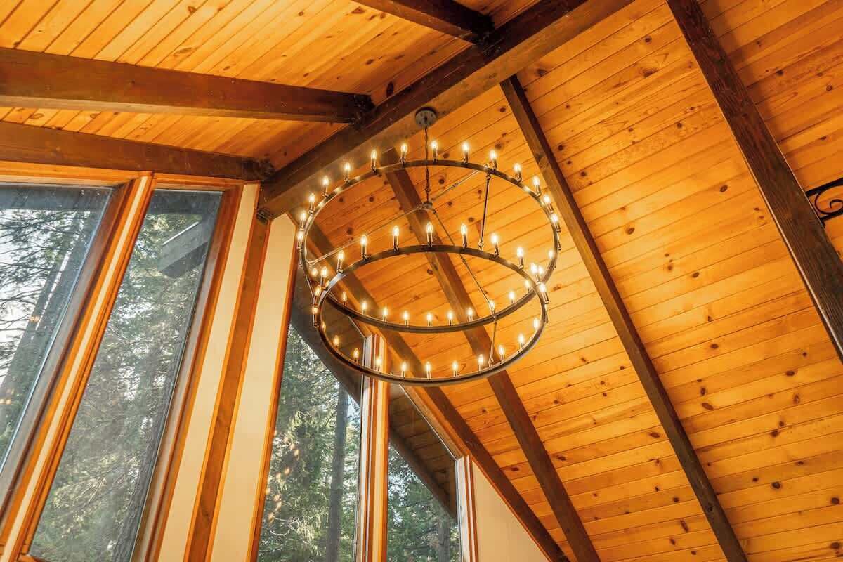 Eine Holzbalkendecke mit einem runden Kronleuchter und großen Fenstern.