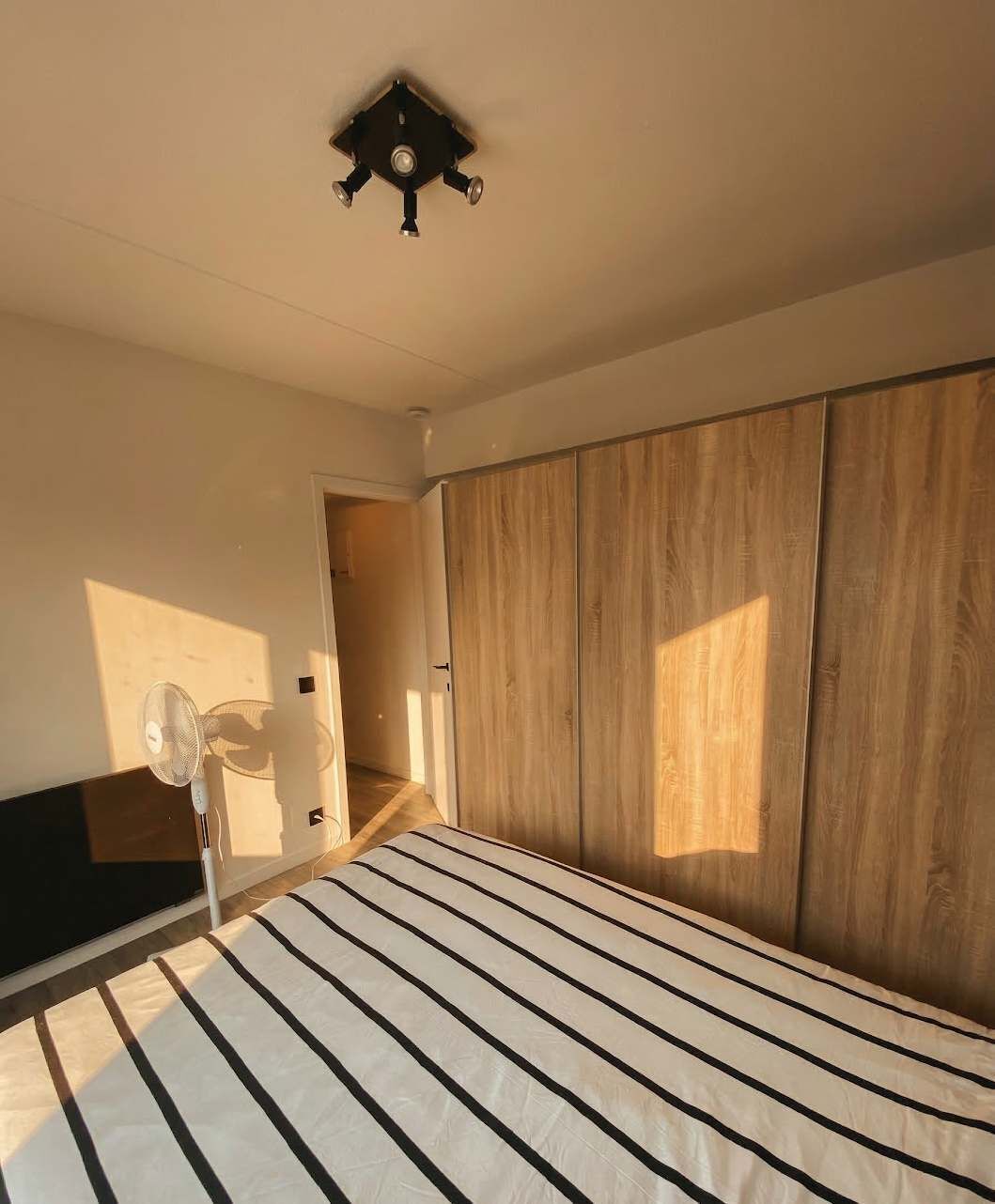 Une chambre à coucher avec un lit, un ventilateur de plafond et une armoire.