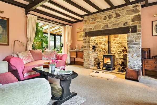 A cozy living room with a stone fireplace, a sofa, a coffee table, and a view of the outdoors. - Vine Barn (Bellerby)