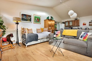 Ein gemütliches Wohnzimmer mit Bett, Sofa, Esstisch und Küchenzeile.