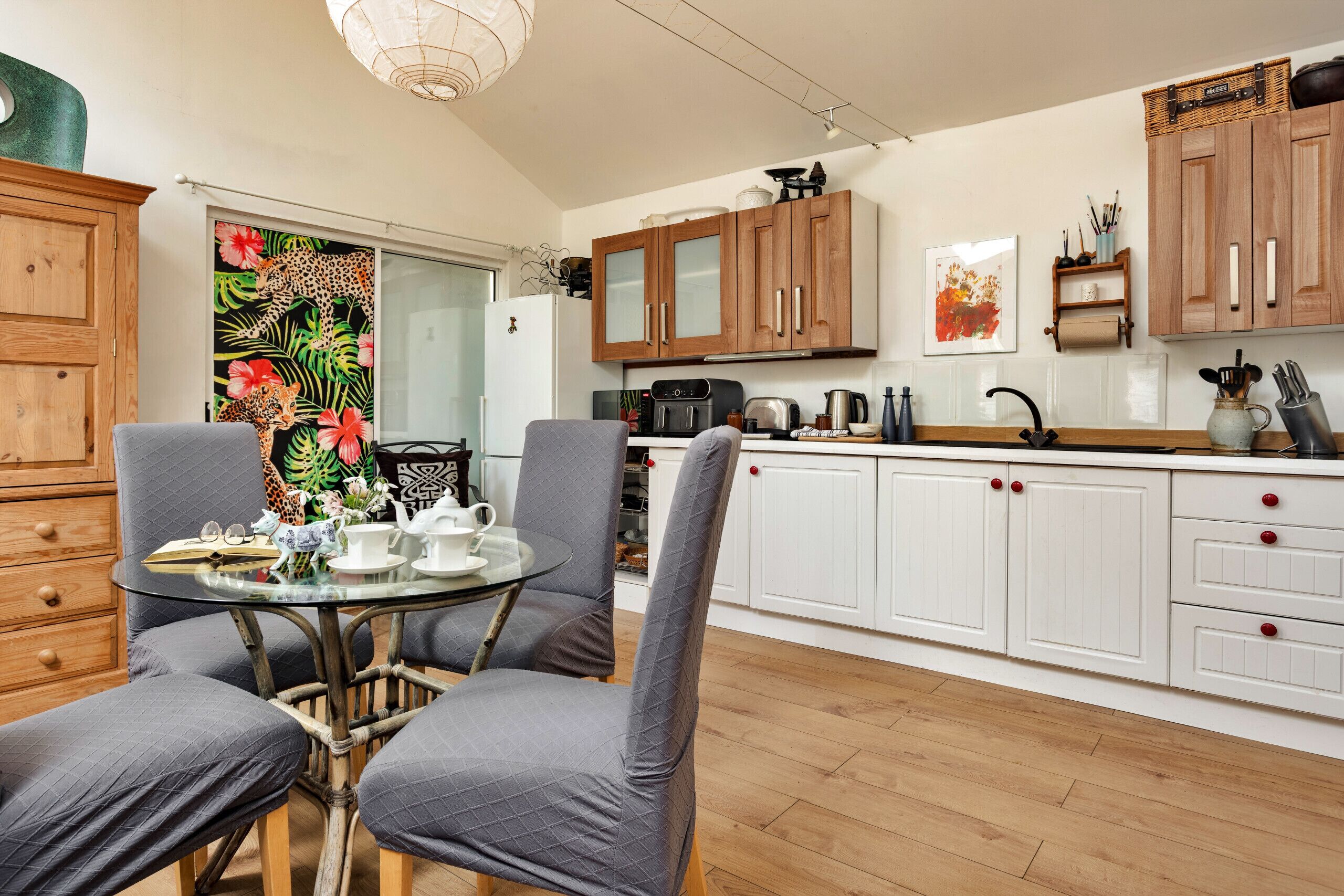 Een moderne keuken met witte kastjes, een eettafel met stoelen en uitzicht op de woonkamer.