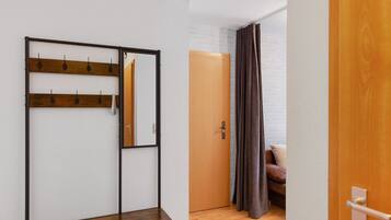 Una habitación con un banco de madera, un perchero, una puerta y una cortina marrón.