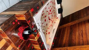 A wooden floor with a white bathtub filled with rose petals and two wine glasses. - VASTO HORIZONTE TURISMO (Barreirinhas)
