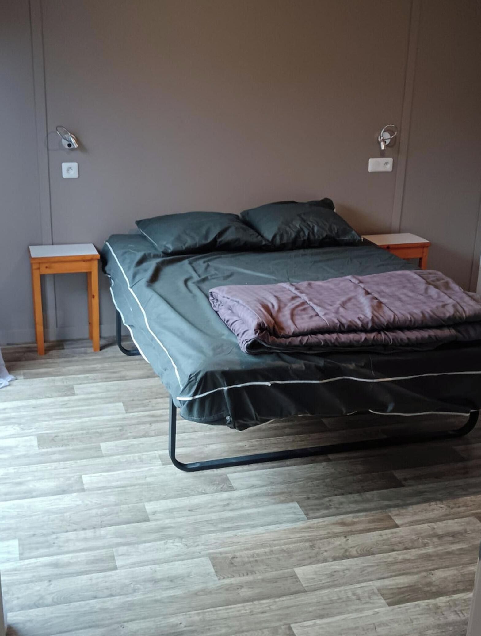 Ein Zimmer mit einem Bett, zwei Nachttischen und Holzboden.