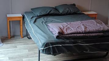 Ein Zimmer mit einem Bett, zwei Nachttischen und Holzboden.