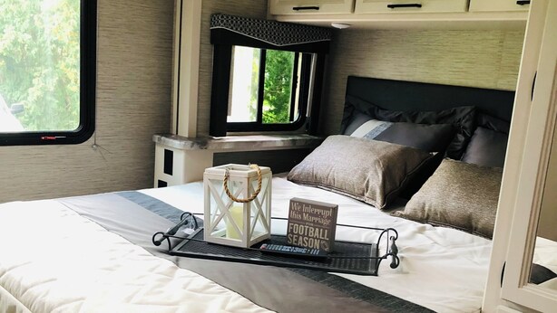Ein Schlafzimmer mit einem Bett, Nachttischen, einem Fenster und Blick auf Grün.