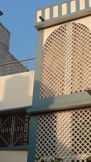 A building with a geometric facade, a visible window, and a metal railing. - Shri Jee Kunj Homestay (Varanasi)