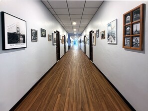 A hallway with framed pictures on the walls, wooden flooring, and doors leading to rooms.