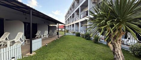 A building with multiple balconies, a grassy courtyard, and outdoor seating.
