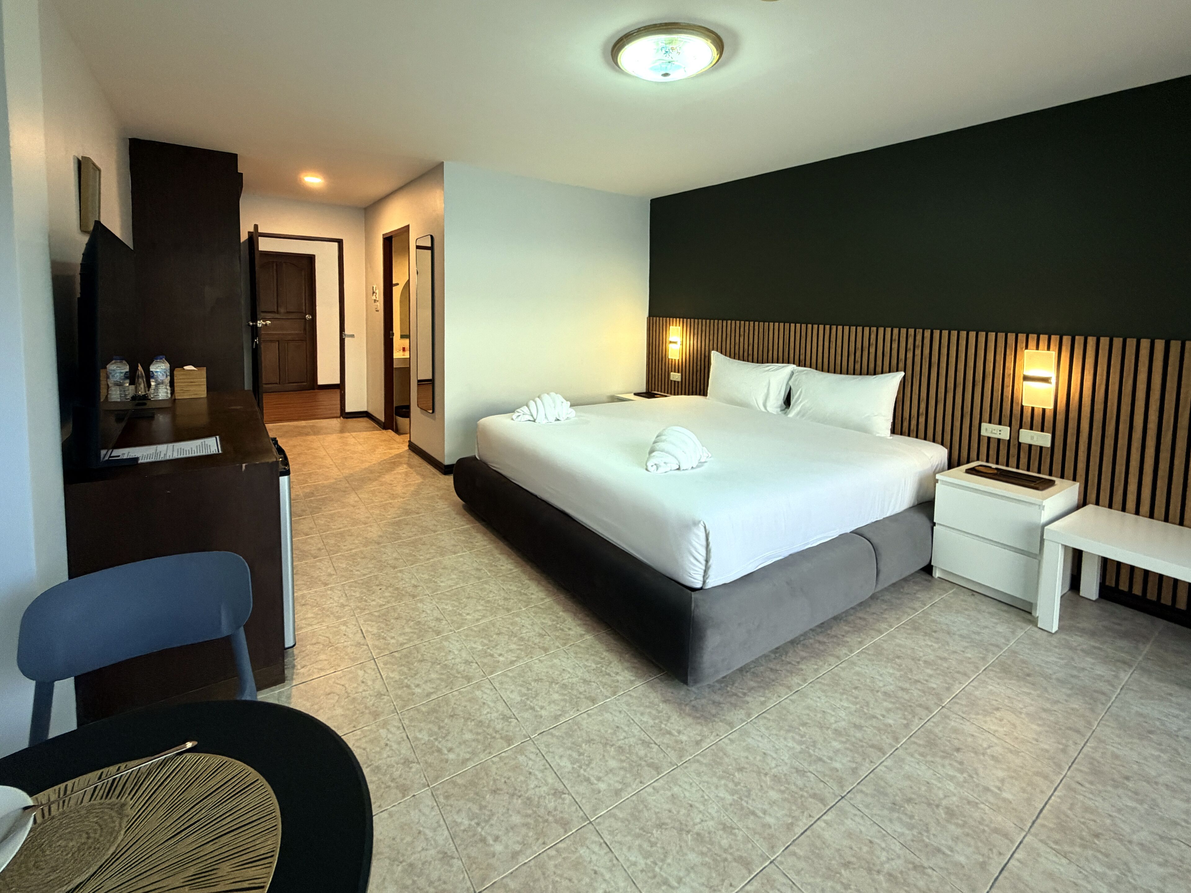 Una habitación de hotel con cama, mesitas de noche, escritorio, silla y televisor.