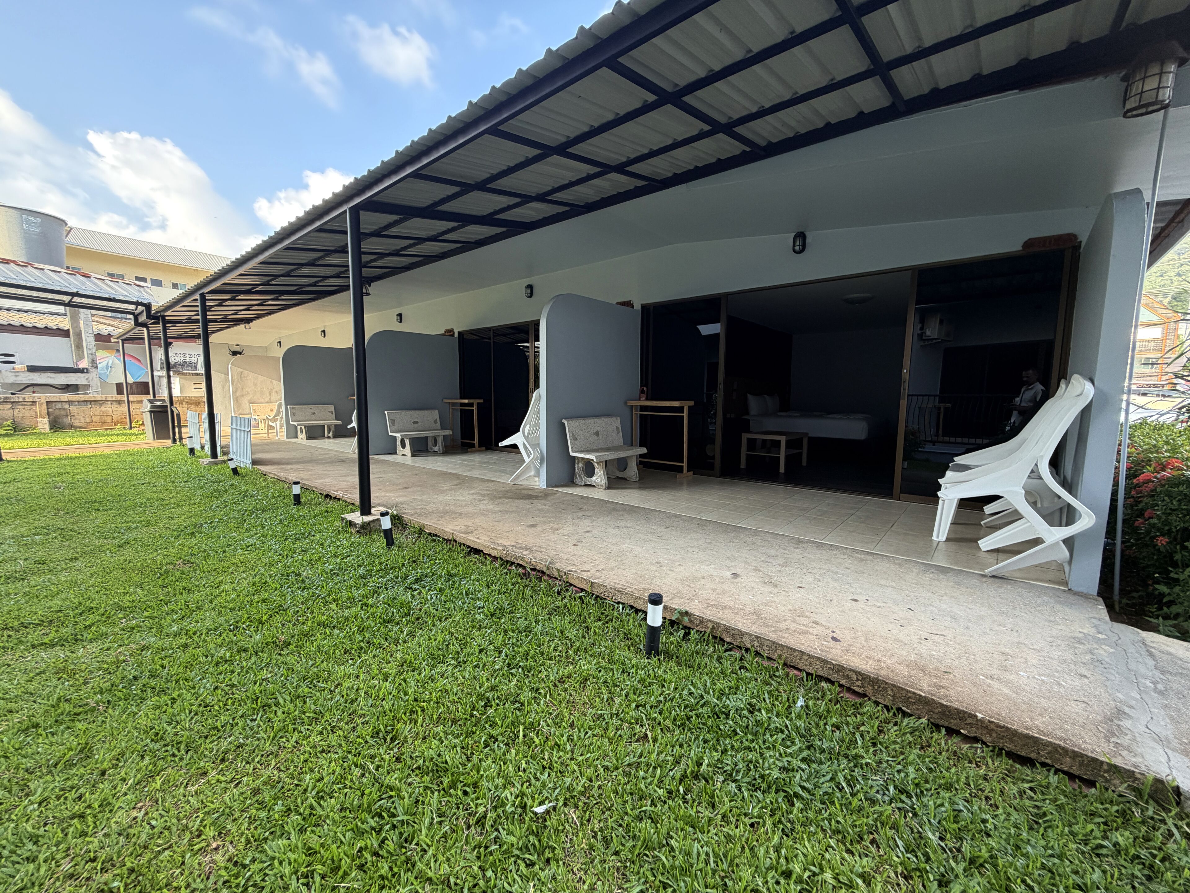 A covered outdoor seating area with concrete flooring, benches, and tables.