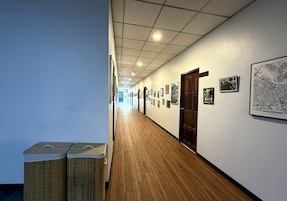 A hallway with wooden flooring, framed pictures on the walls, and a map of Amsterdam.