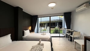 A hotel room with two beds, a desk, a chair, and a view of the outside.