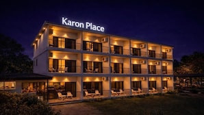 A multi-story hotel named 'Karon Place' with balconies and outdoor seating areas.