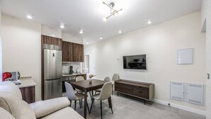 Una cocina moderna con refrigerador empotrado, armarios de madera y un comedor con mesa y sillas.