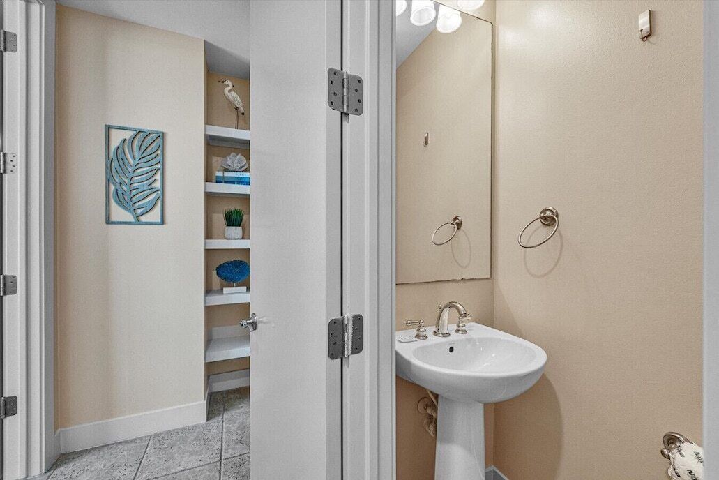 Un baño con un lavabo blanco, un espejo y una repisa con adornos.