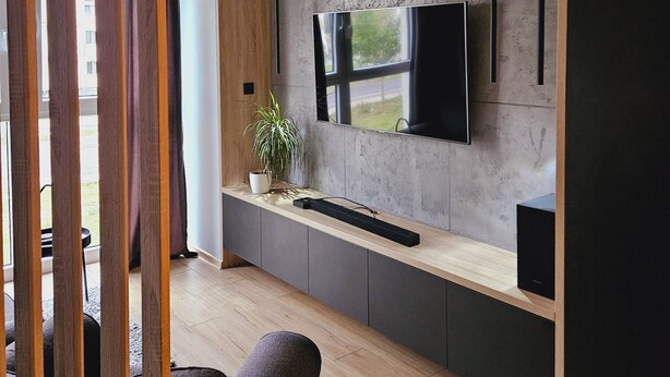 Ein modernes Interieur mit integriertem Fernseher, Holzvertäfelung, einer Topfpflanze und einer Sitzecke.