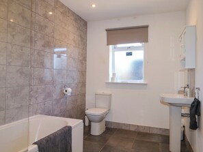 A bathroom with a bathtub, toilet, and sink. - Snowdrop Cottage (Maidstone)