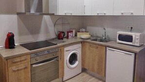 A compact kitchen with a washing machine, microwave, sink, and a coffee maker. - Spacious 4-bedroom condo in tranquil Alcalá de Henares -One-Bedroom Apartment (Alcalá de Henares)