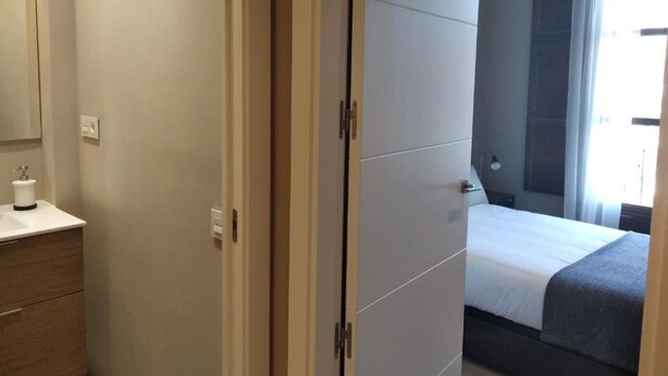 A bedroom with a bed, a nightstand, and a window with curtains. - Spacious 4-bedroom condo in tranquil Alcalá de Henares -One-Bedroom Apartment (Alcalá de Henares)