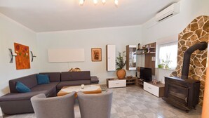 Una sala de estar con sofá, dos sillones, una mesa de centro, televisor, chimenea y elementos decorativos.