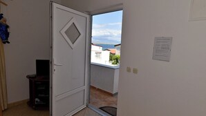 Habitación con una puerta blanca, un pequeño mueble para televisión y vistas a un edificio y al agua.