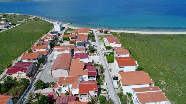 Vista aérea de una zona residencial costera con casas, una carretera y una playa.