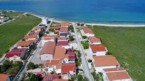 An aerial view of a coastal residential area with houses, a road, and a beach. - Apartments Karacic (Vir)
