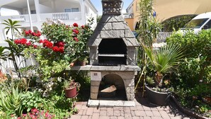 Un horno de piedra al aire libre rodeado de macetas con plantas y flores.