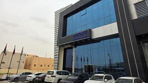 A modern building with a large glass facade, a sign for 'Cityview Apartments,' and several parked cars in front. - Palette Ninty (Riyadh)