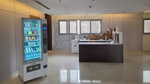 A modern hotel lobby with a vending machine, a marble wall, and a reception desk. - Palette Ninty (Riyadh)
