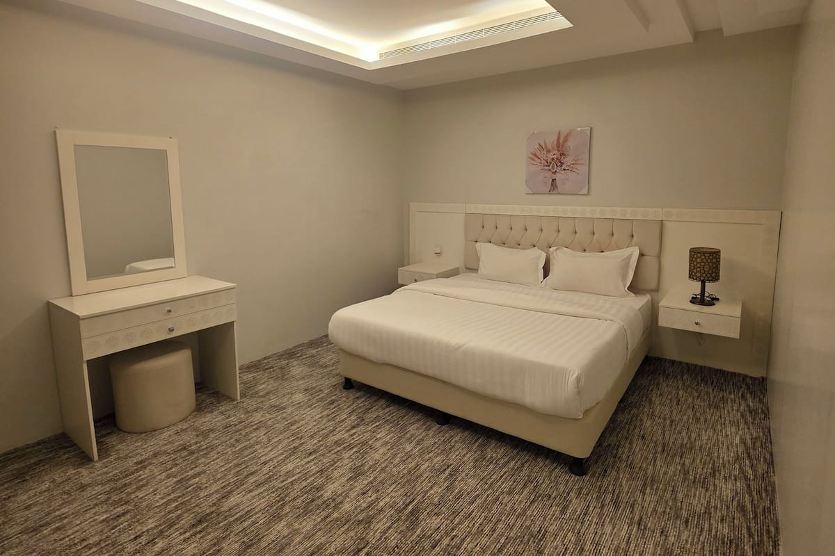 A bedroom with a bed, bedside table, nightstand, and a ceiling light fixture.