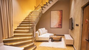 Un intérieur moderne avec un escalier, un canapé, une table basse et un téléviseur à écran plat.